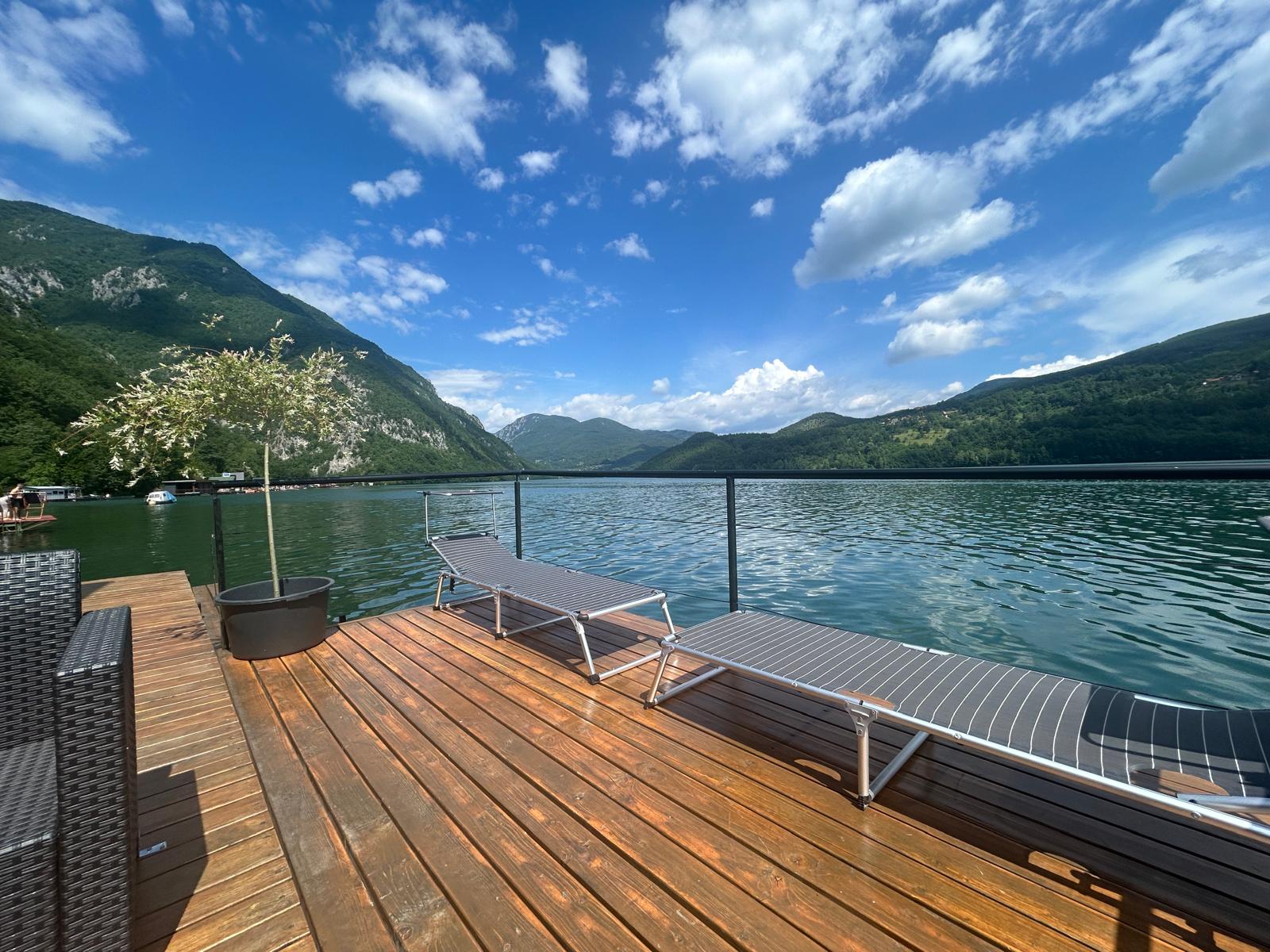 Ležaljke na terasi sa pogledom na jezero i planine